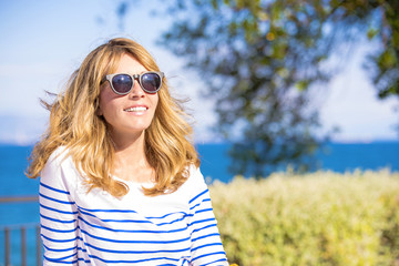 Enjoy summer by the sea. Beautiful mature woman relaxing on balcony.