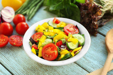 Fresh salad in bowl on wooden background