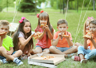 Children eating pizza on grass