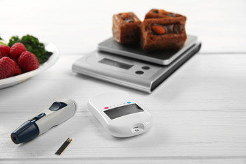 Glucose meter with fruits and cookies on table