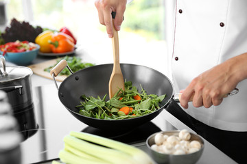 Male hand mixing vegetables in pan closeup