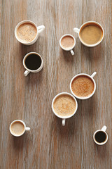 Cups of coffee on wooden background, top view
