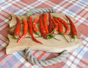 Eleven fresh red chili peppers on a handmade wooden board under a daylight - 120160425