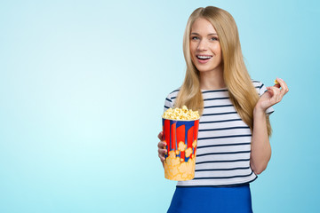Beautiful girl eating popcorn on white background