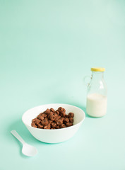 Chocolate cereal in bowl with milk on blue background.