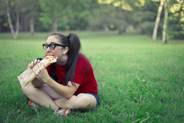 Cute young girl eating a slice of pizza