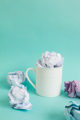 Creative concept, Crumpled paper in coffee cup on blue background.