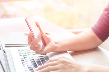 Close Up of woman hands using mobile phone and laptop computer business with blank copy space screen for your business advertising text message or content business in the morning light.