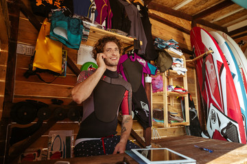 Man in swimsuit talking on smartphone in the surf shack