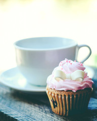 Cup of coffee and cupcake on wooden table