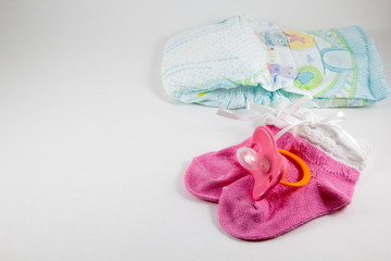 Pacifier, booties, baby diaper on a white background