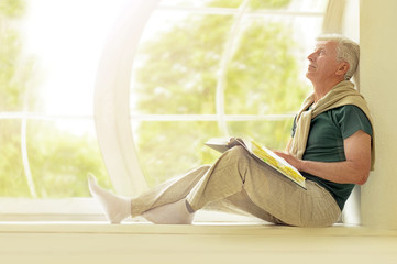 Senior man with book at home