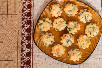 Obraz na płótnie Canvas Muffins with salmon, spinach and cheese a big brown plate on tablecloth. Aerial view.
