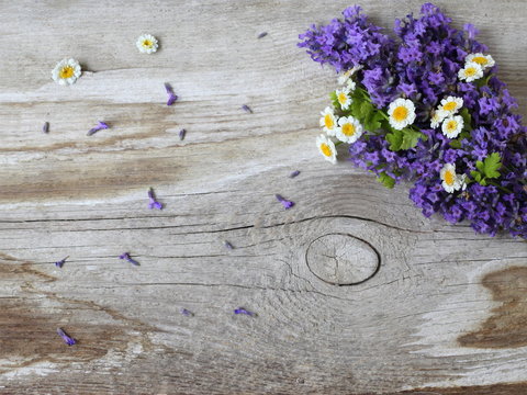 Natural background with bouquet of lavender and daisy flowers on a wooden plank. Top view of a bunch of daisies and purple lavandula flowers on a wooden background. Photo from above.