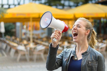 Angry young woman yelling into a megaphone
