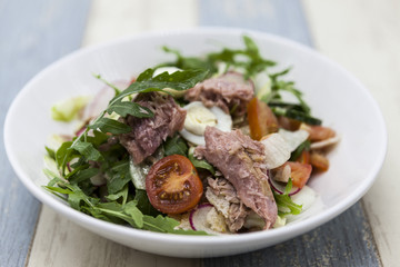 Delicious fresh vegetable salad with tuna on a white porcelain plate.