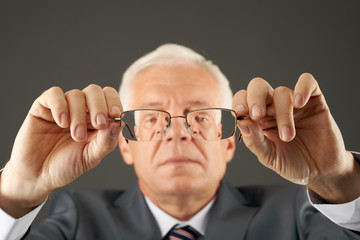 Portrait of senior man with eyeglasses in hands