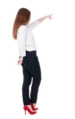 Back view of young redhead business woman pointing at wall. beautiful girl in dark suit. Rear view people collection. backside view of person. Isolated over white background.