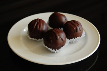 Assorted dark chocolate truffles with cocoa powder, coconut and chopped hazelnuts on a dessert plate