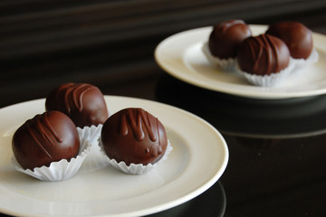 Assorted dark chocolate truffles with cocoa powder, coconut and chopped hazelnuts on a dessert plate