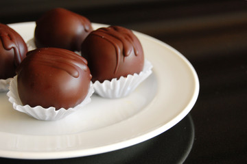 Assorted dark chocolate truffles with cocoa powder, coconut and chopped hazelnuts on a dessert plate