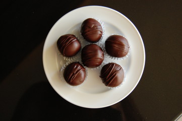 Assorted dark chocolate truffles with cocoa powder, coconut and chopped hazelnuts on a dessert plate