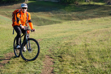 Obraz premium Young man traveler riding on bicycle with red backpack