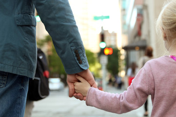 father holding  the daughter/ child  hand  behind  the traffic l