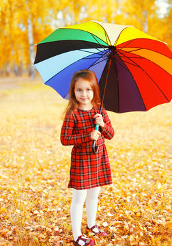 Happy little girl child with colorful umbrella in autumn day