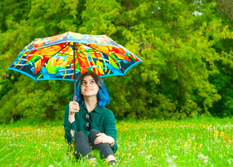 Teen girl with blue hair under umbrella in summer park