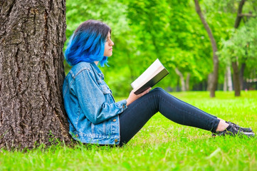 Teen girl reading book in park