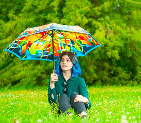 Young girl under colorful umbrella in park