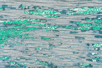 Old wooden wall with cracked and peeling green paint. Textured background.