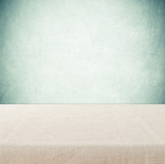 Empty table with linen tablecloth over cement wall background