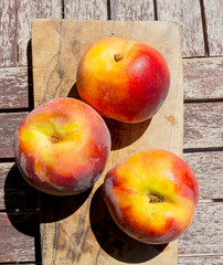 Tre pesche su un tagliere: frutta in tavola