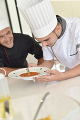 Fototapeta na wymiar Cook student preparing dish with help of chef