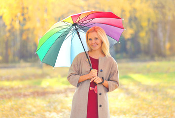 beautiful smiling woman with colorful umbrella in warm sunny aut
