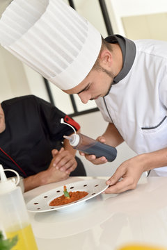 Cook student preparing dish with help of chef