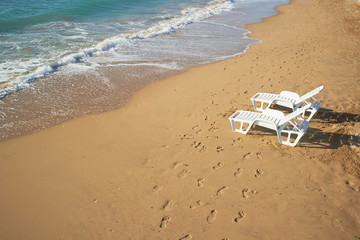 Fototapeta na wymiar two loungers on the beach near the shore