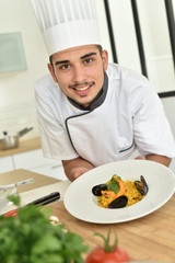 Young chef in cooking training school presenting dish