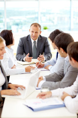 Group of business colleagues listening to a businessman during a meeting in a conference room