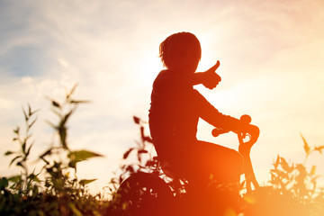 Obraz na płótnie Canvas little boy riding bike at sunset, active kids
