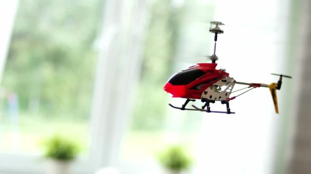 Red toy helicopter flying in home
