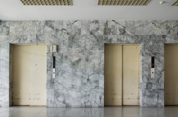 old and obsolete lift decorated with marble wall at the entrance of old building
