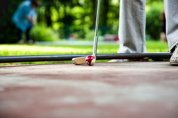 Ein Minigolfer beim langen Einputten vom Bahnrand. Er benutzt einen Ball mit der zeichnung der 15 des Billards . 