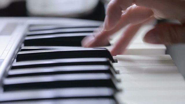 Woman hand playing a MIDI controller keyboard synthesizer close up.