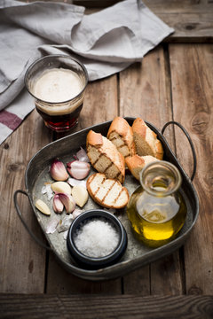 Sliced garlic bread, baguette, garlic, sea salt and olive oil on tray
