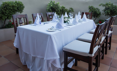 Festively laid table with white tablecloths  glasses and plates