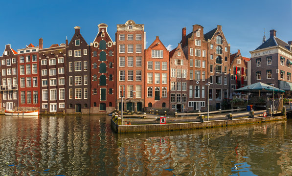 Panorama with beautiful typical Dutch dancing houses at the Amsterdam canal Damrak in sunny day, Holland, Netherlands.