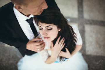 Groom embraces his bride from behind